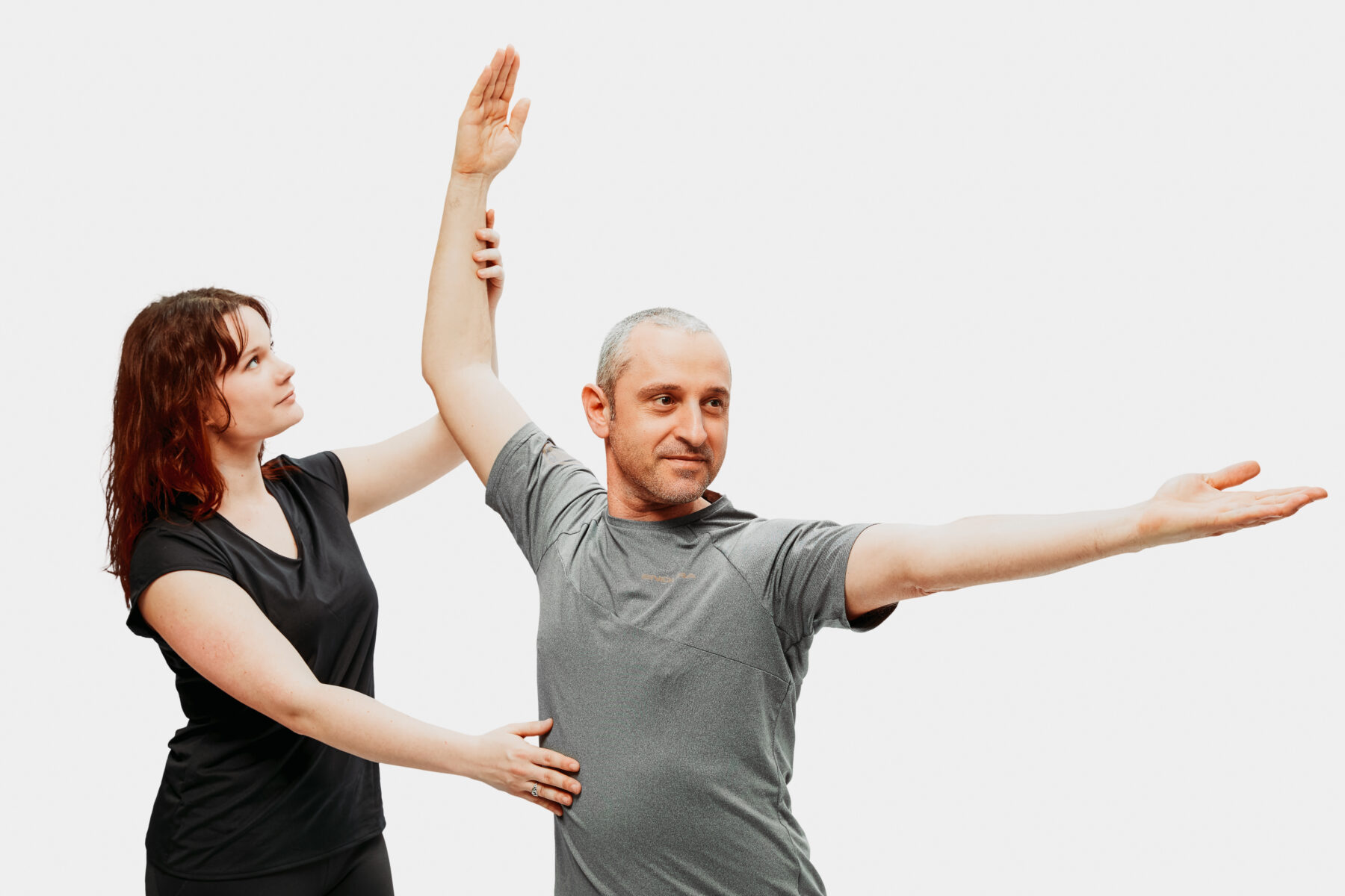 Therapeutin unterstützt einen Mann bei einer Arm- und Schulterübung zur Verbesserung von Haltung und Beweglichkeit.